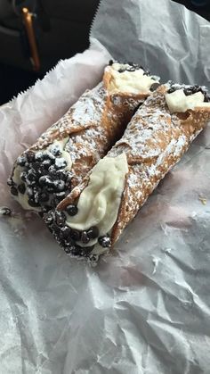 two pastries sitting on top of a piece of wax paper covered in powdered sugar