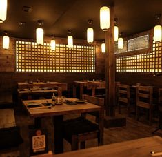 a dimly lit restaurant with wooden tables and lanterns hanging from the ceiling, along with wood flooring