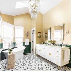 an ornate bathroom with green and white tiles on the floor, chandelier above the bathtub