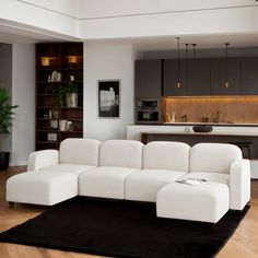 a large white couch sitting on top of a wooden floor next to a black rug