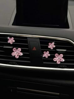 pink flowers on the dashboard of a car with black dash board and air vent cover