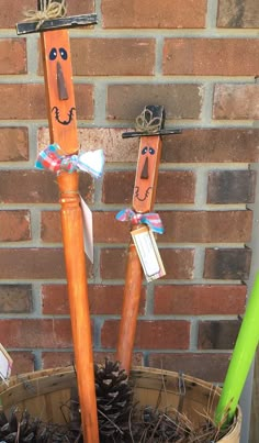 three wooden sticks with faces on them are in a basket next to a brick wall