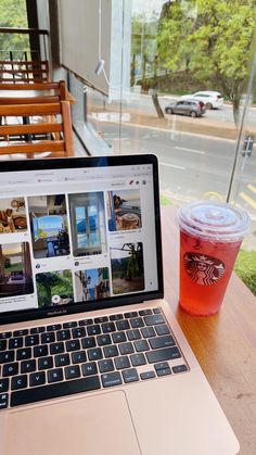 an open laptop computer sitting on top of a wooden table next to a cup of tea