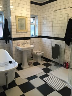 a bathroom with black and white checkered flooring on the walls, tub, toilet and sink