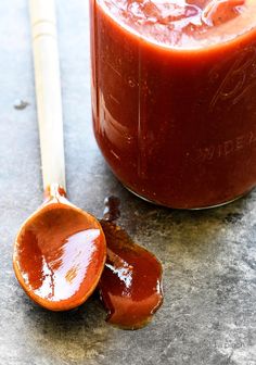 a spoon full of sauce sitting next to a jar