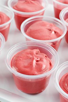 plastic cups filled with pink colored food on top of a white tray, ready to be eaten