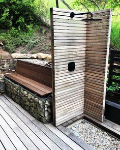 a wooden bench sitting on top of a wooden deck next to a shower stall with stone walls