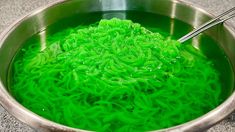 the bowl is full of green noodles with chopsticks sticking out of it's top