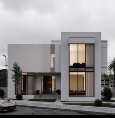 a white modern house with large windows on the front and side walls, along with cars parked outside