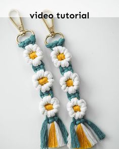 two white and yellow tasselled keychais with flowers on each side, one is