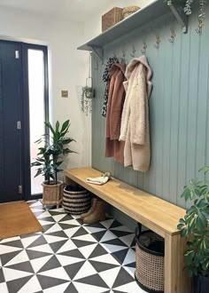 a coat rack with two coats hanging on it next to a black and white checkered floor