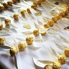 many pieces of gold foiled chocolate on a white table cloth with names and numbers