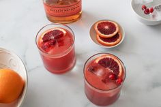 two glasses filled with blood orange juice and garnished with pomegranates