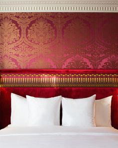 a bed with two lamps on either side of it and a red wall behind it