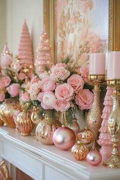 pink and gold christmas decorations on a mantel with candles, ornaments and flowers in vases