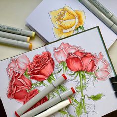 some markers and pens are on top of two notebooks with roses drawn on them