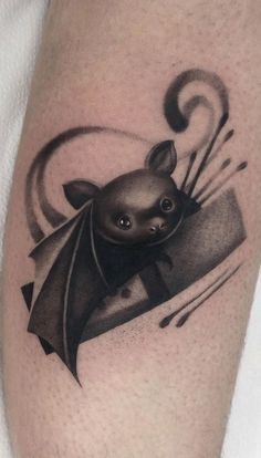 a black and white photo of a bat tattoo on the leg with an ink design