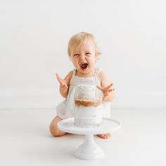 a baby sitting on the floor with a cake in front of her