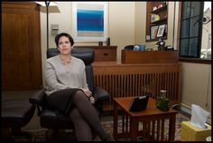 a woman sitting in an office chair with her legs crossed and looking off to the side