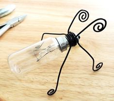 a light bulb sitting on top of a wooden table next to scissors and a pen