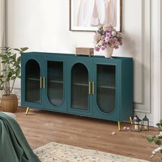 a living room with a blue cabinet and flowers on the sideboard in front of it