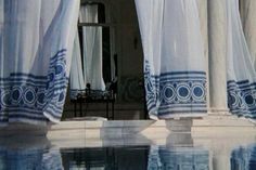 an open window with curtains on the outside and reflecting water in the pool below it