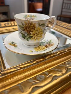 a tea cup and saucer with flowers painted on the side sitting on a table