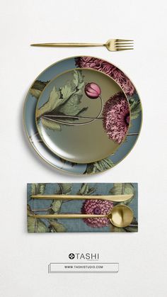 two plates with flowers on them and gold spoons next to each other in front of a white background