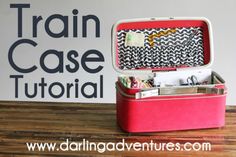 an open pink suitcase sitting on top of a wooden table next to a sign that says train case