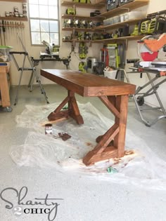 a workbench in a garage with tools on the floor and shelves above it