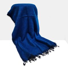 a blue towel with black fringes on it sitting on top of a white table