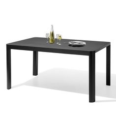 a black table with two glasses and plates on it, next to a bottle of wine