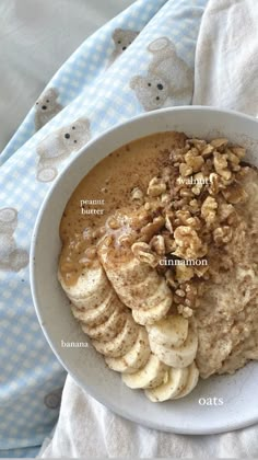 a white bowl filled with oatmeal and bananas on top of a blanket