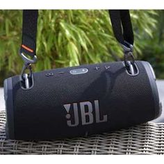 the jbl boom is sitting on top of a wicker table with trees in the background