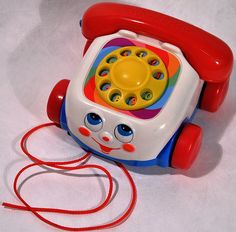 a toy phone sitting on top of a red cord next to a white tablecloth