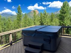 a hot tub sitting on top of a wooden deck next to trees and mountains in the background