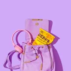 a purple purse with earphones on it and a yellow packet in the back pocket