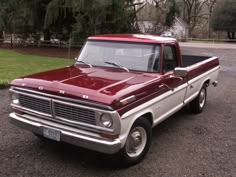 an old red pickup truck parked in a parking lot