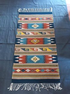 a blue rug with fringes on the bottom and an orange, yellow, green, red