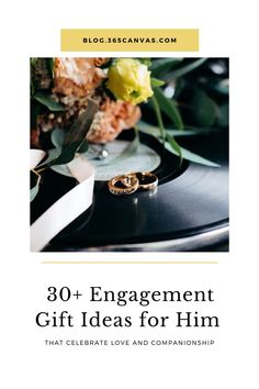 two wedding rings on top of a record with flowers and greenery in the background