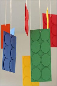 three legos are hanging from strings made out of construction paper and colored circles on them