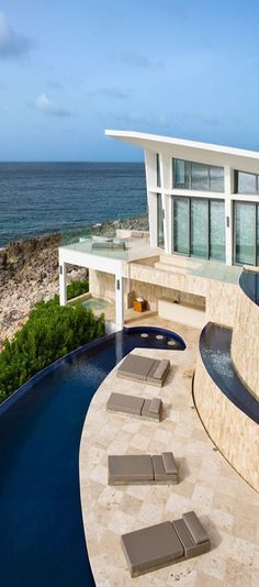 an outdoor swimming pool with chaise lounges next to the ocean