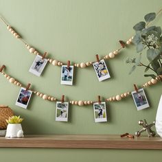 some pictures are hanging on a string with clothes pins attached to them and there is a plant in the corner