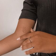 two hands holding each other with small tattoos on their arm and wrist, one has a leaf tattoo on it's left hand