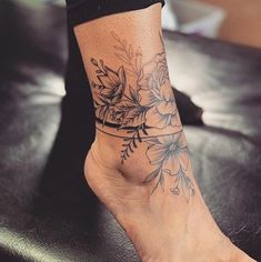 a woman's foot with flowers on it and a tattoo design on the ankle