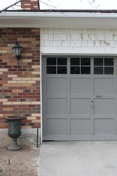 a gray garage door in front of a brick building