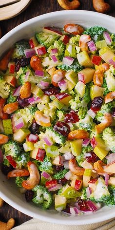 a bowl filled with broccoli, apples, raisins and cranberries