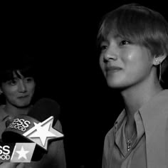 black and white photo of two people with microphones in front of one person holding a star shaped object