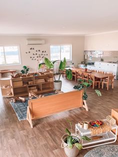 a living room filled with lots of furniture and plants on top of wooden flooring