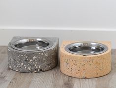 two concrete bowls sitting next to each other on a wooden floor